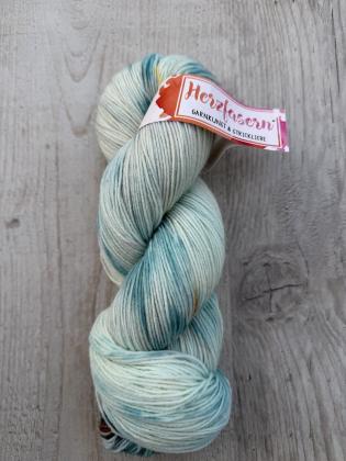 Mehrere handgefärbte Garnstränge der Marke Herzfasern liegen nebeneinander. Die Färbung „Klarheit“ zeigt ruhige, helle und ausgewogene Farbtöne mit sanften Übergängen. Die Gesamtwirkung ist klar und harmonisch.