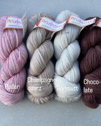Vier Stränge handgefärbte Wolle liegen nebeneinander. Von links nach rechts: ein zartes Rosé (Puder), ein edles Beige (Champagnerquarz), ein helles, cremefarbenes Weiß (Perlmutt) und ein tiefes, warmes Braun (Chocolate).