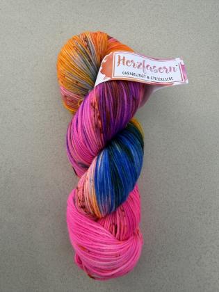 Handgefärbter Wollstrang in leuchtendem Neonpink mit kräftigen Violett-, Orange-, Blau- und Petroltönen. Dunkle Sprenkel durchziehen die Färbung und sorgen für lebendige Farbkontraste. Gefärbt auf Herzfasern No. 21.