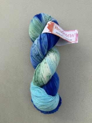 Handgefärbter Wollstrang in kräftigem Blau, Aqua, Mint und Weiß mit feinen dunkelgrünen Sprenkeln. Die Farbgebung erinnert an Meerwasser, Wellen und einen klaren Himmel. Gefärbt auf Herzfasern No. 21.