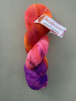 Handgefärbter Wollstrang „Ein echter Cornelius“ auf Herzfasern No. 21 in Neonpink, Orange, Koralle und Violett mit feinen dunklen Sprenkeln.