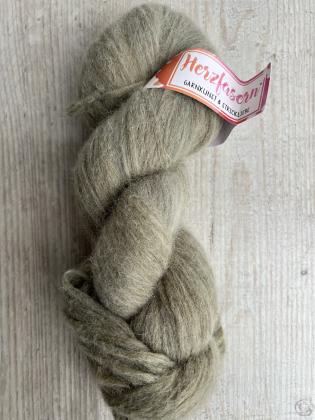 Das Bild zeigt einen flauschigen Strang Herzfasern No. 42 in einem sanften, olivgrünen Naturton. Die Farbe wirkt leicht meliert und weich. Der Strang liegt auf einer hellen Holzoberfläche, oben ist das Herzfasern-Etikett sichtbar.