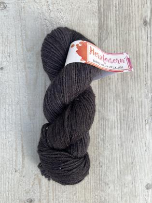 Handgefärbter Wollstrang Herzfasern No. 46 aus Alpaka und Bio-Schurwolle in tiefem, warmem Dunkelbraun („Schokoschatten“), mit matter Oberfläche und sichtbarem Alpaka-Flaum, fotografiert auf hellem Holzuntergrund.