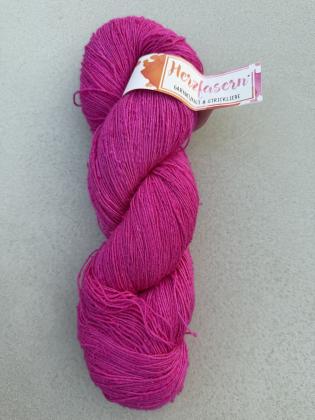 Ein handgefärbter Strang Tussahseide in kräftigem Pink liegt auf hellem Untergrund. Die feine, leicht unregelmäßige Garnstruktur mit kleinen Noppen ist gut sichtbar. Eine Banderole mit der Aufschrift „Herzfasern“ ist am Strang befestigt.