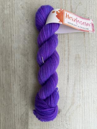 Handgefärbter Strang Herzfasern No. 94 Kaschmir-Cloud in kräftigem, sattem Lila auf hellem Holzhintergrund mit Herzfasern-Banderole.