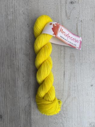 Handgefärbter Strang Herzfasern No. 94 Kaschmir-Cloud in kräftigem, leuchtendem Gelb auf hellem Holzhintergrund mit Herzfasern-Banderole.