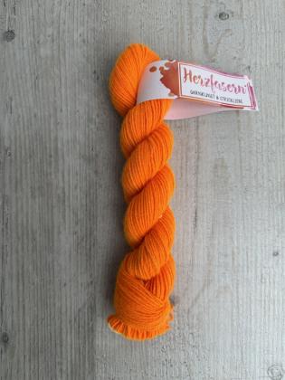 Handgefärbter Strang Herzfasern No. 94 Kaschmir-Cloud in kräftigem Neon-Orange auf hellem Holzhintergrund, mit Herzfasern-Banderole.