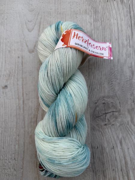 Mehrere handgefärbte Garnstränge der Marke Herzfasern liegen nebeneinander. Die Färbung „Klarheit“ zeigt ruhige, helle und ausgewogene Farbtöne mit sanften Übergängen. Die Gesamtwirkung ist klar und harmonisch.